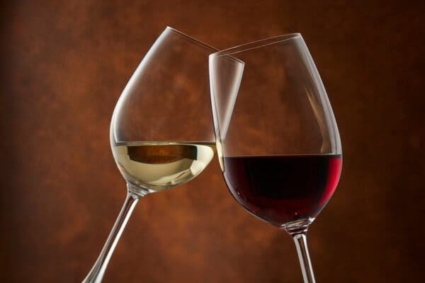 Glass of red wine and white wine toasting.